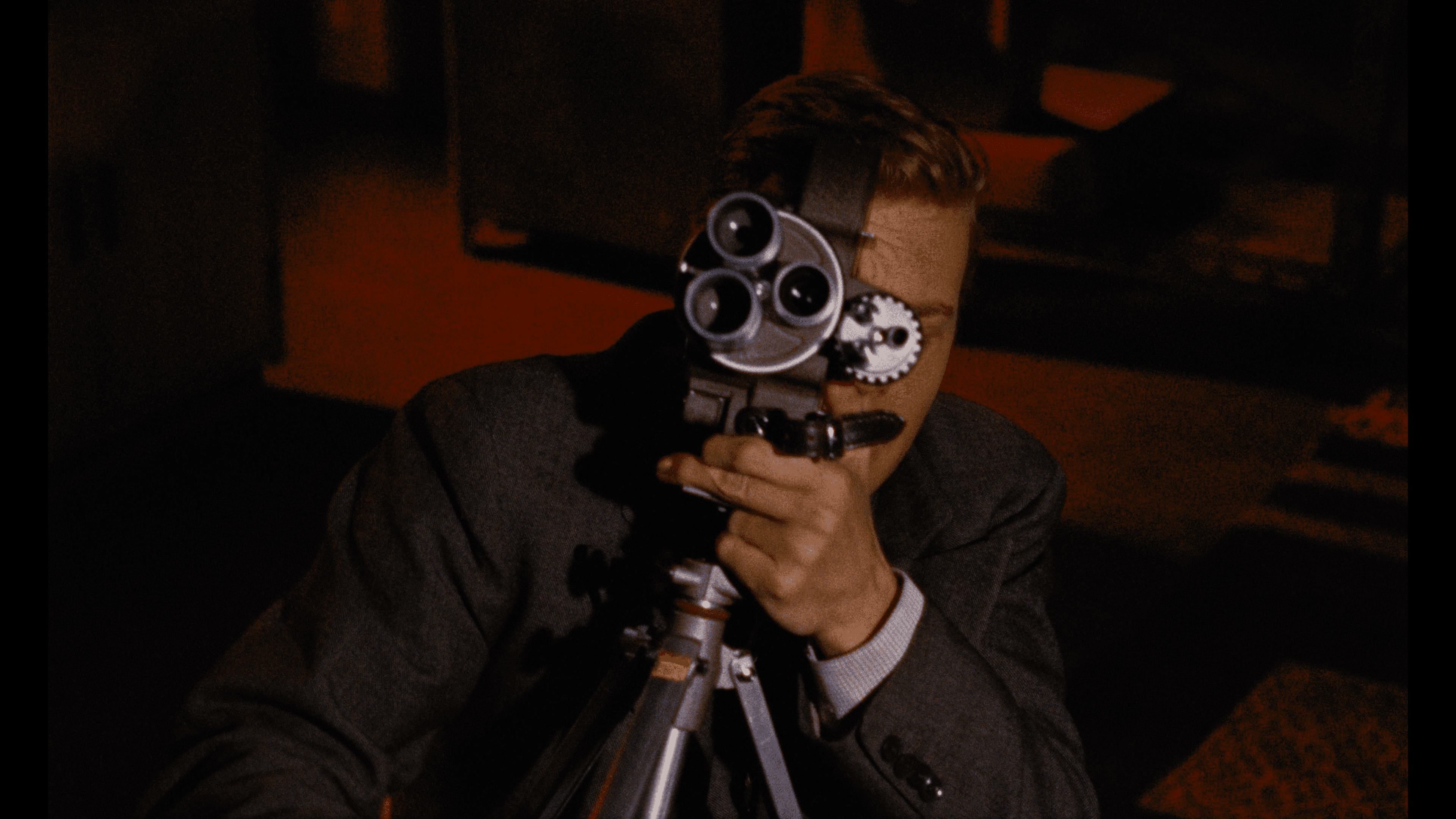 Mark aiming his film camera directly forward, merging the act of filming with the perspective of the viewer