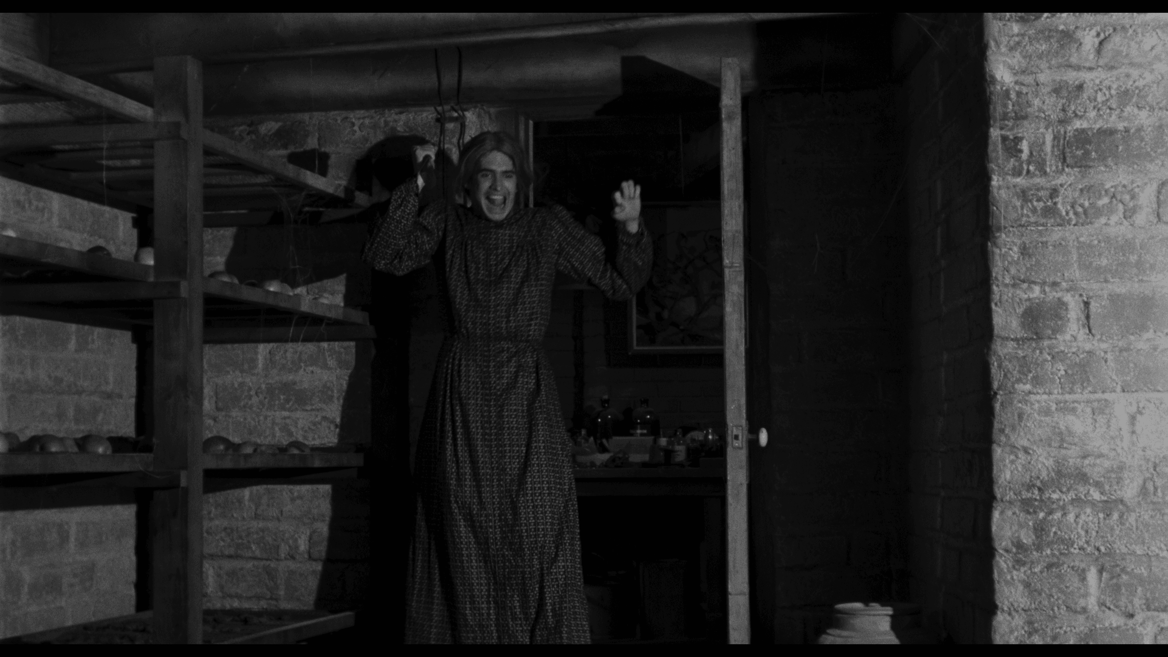 Norman Bates dressed as his mother, caught mid-reveal holding a knife in the basement